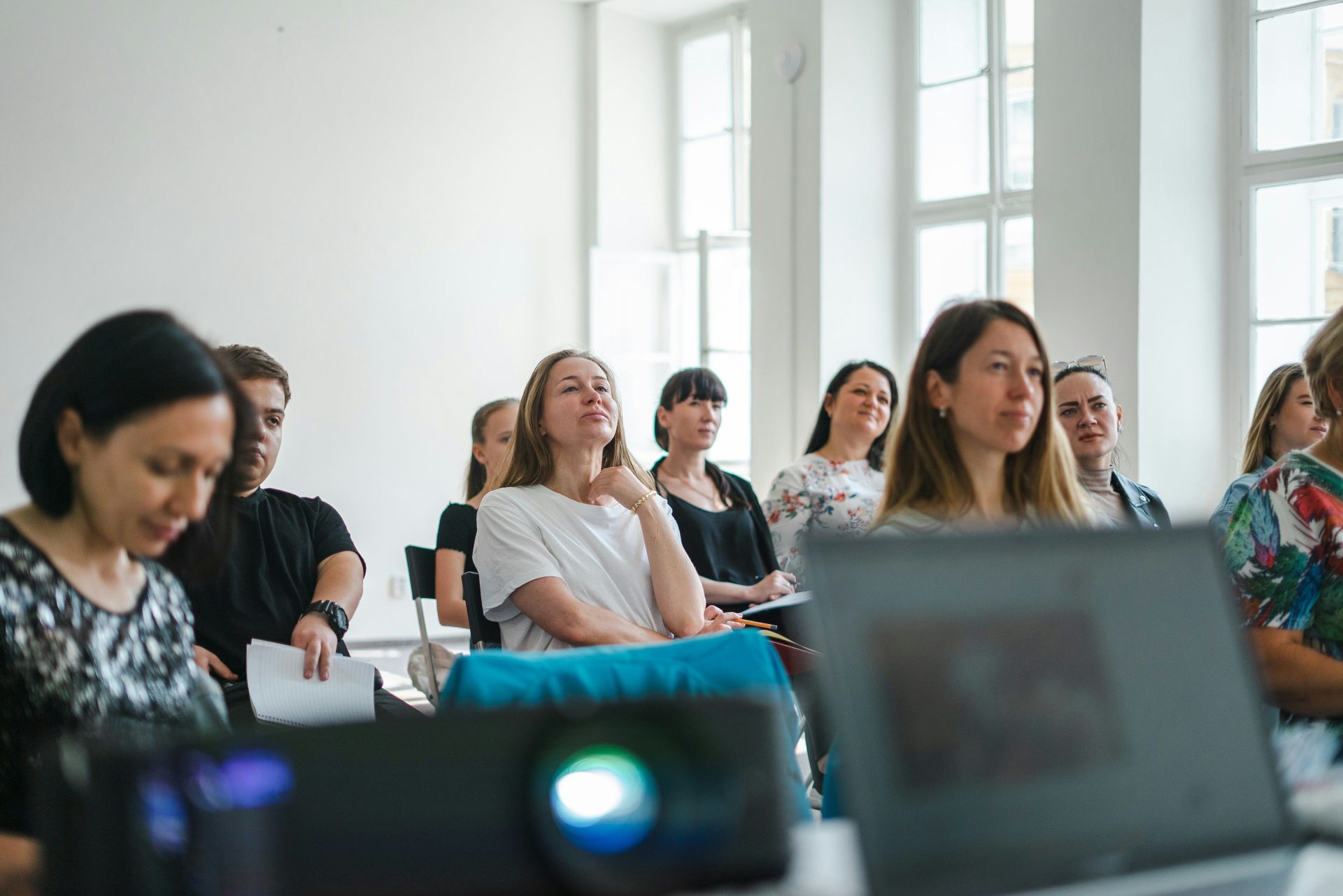 Eine Gruppe von Erwachsenen, die an einem Workshop in einem hellen, sonnendurchfluteten Raum teilnehmen.